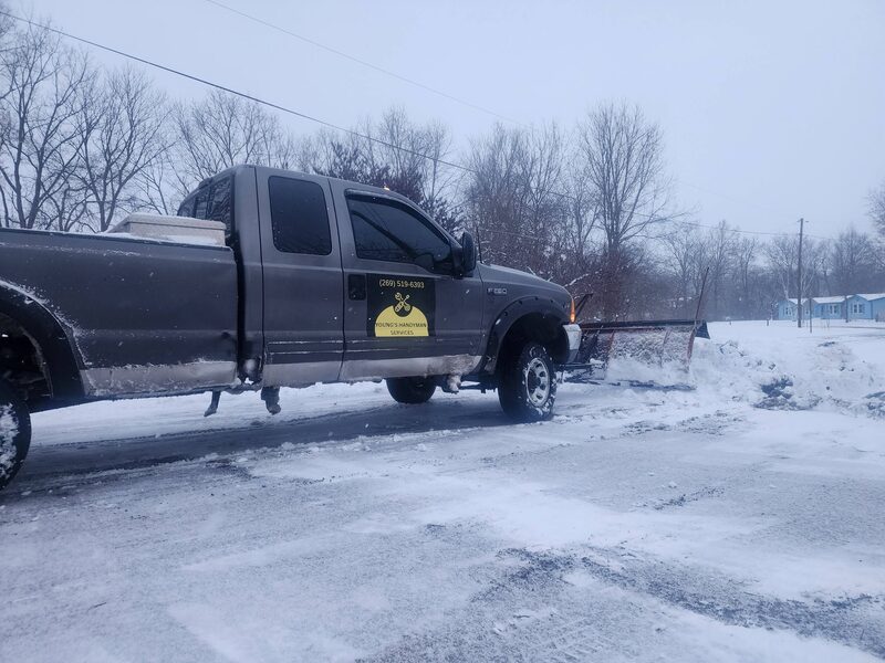 Young's Handyman truck with a plow blade clearing snow on the lakeshore